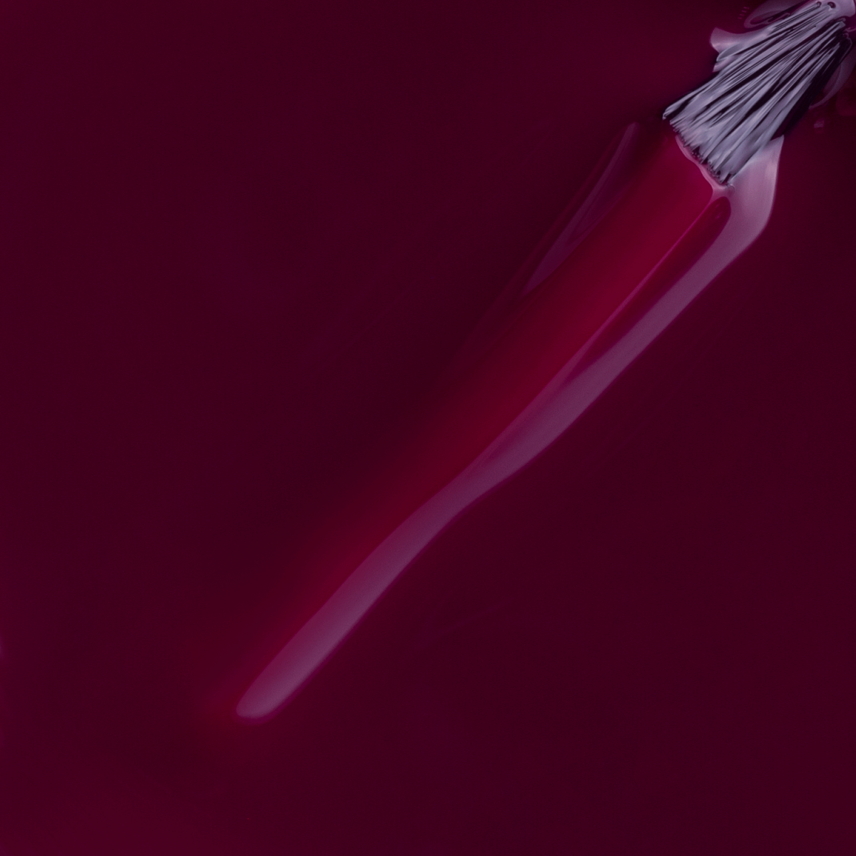 A close-up of an Impala brush spreading glossy, deep Wine Purple Donata from IMPALA Regular Nail Polish Creamy (7.5 ml), with visible bristles and a wet, reflective finish.