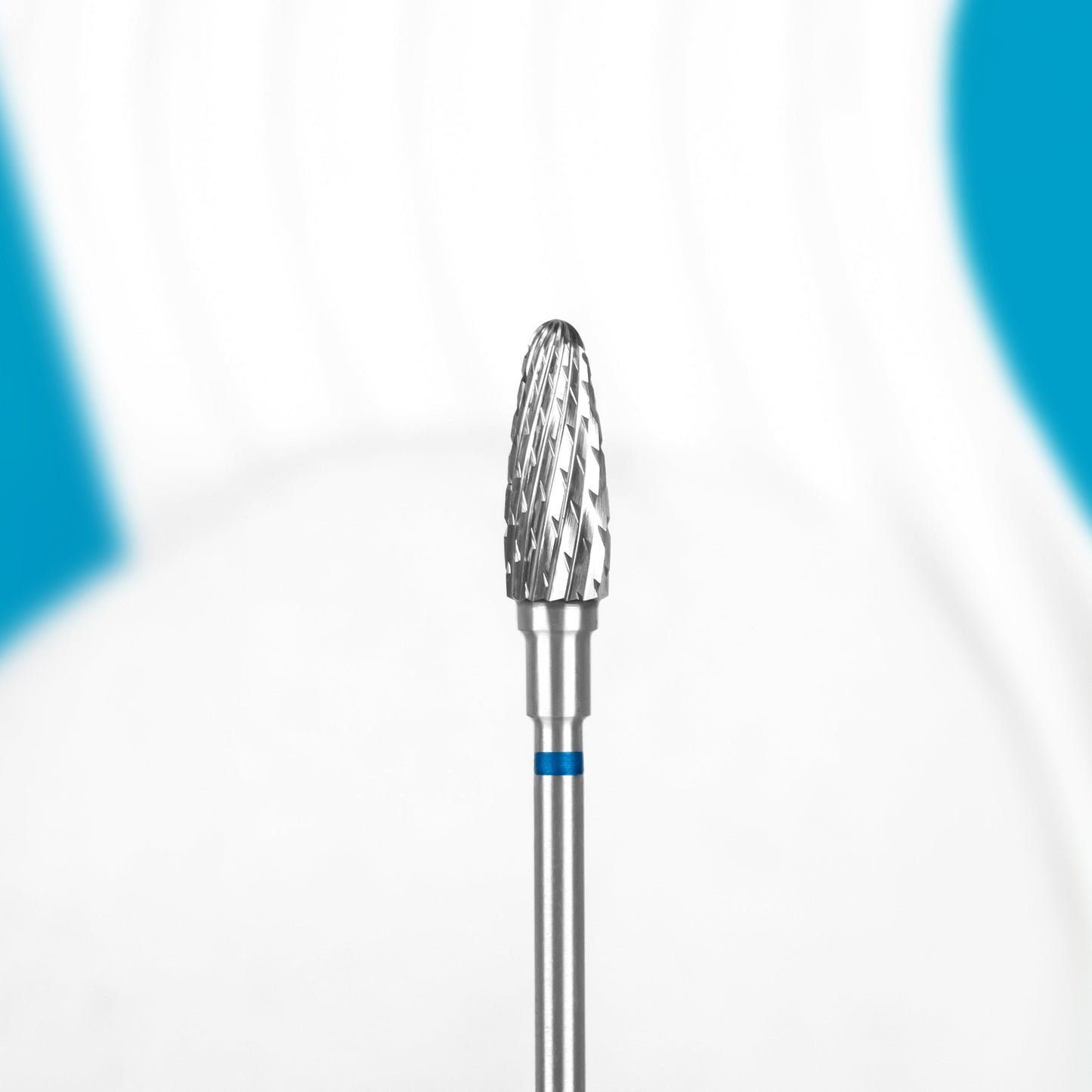 A close-up of the Staleks STALEKS PRO Carbide Nail Drill Bit Corn Blue EXPERT (head diameter 5 mm, working part 13 mm), designed for manicures or shaping artificial nails, shown against a blurred white and blue background.
