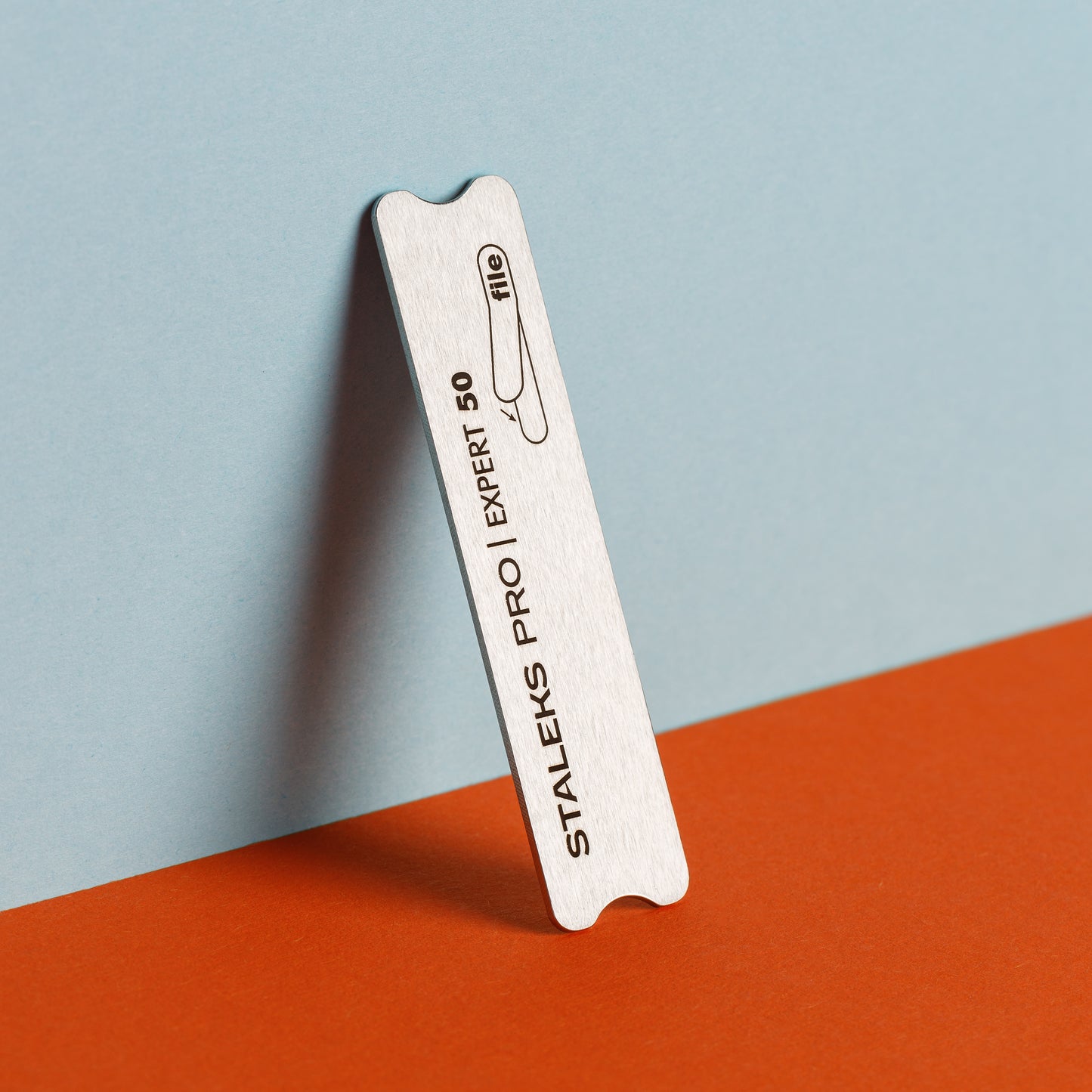 A STALEKS PRO Nail file metal short (base) EXPERT 50 leans against a blue background with the text "Staleks pro expert 50" visible on its side, with an orange base.