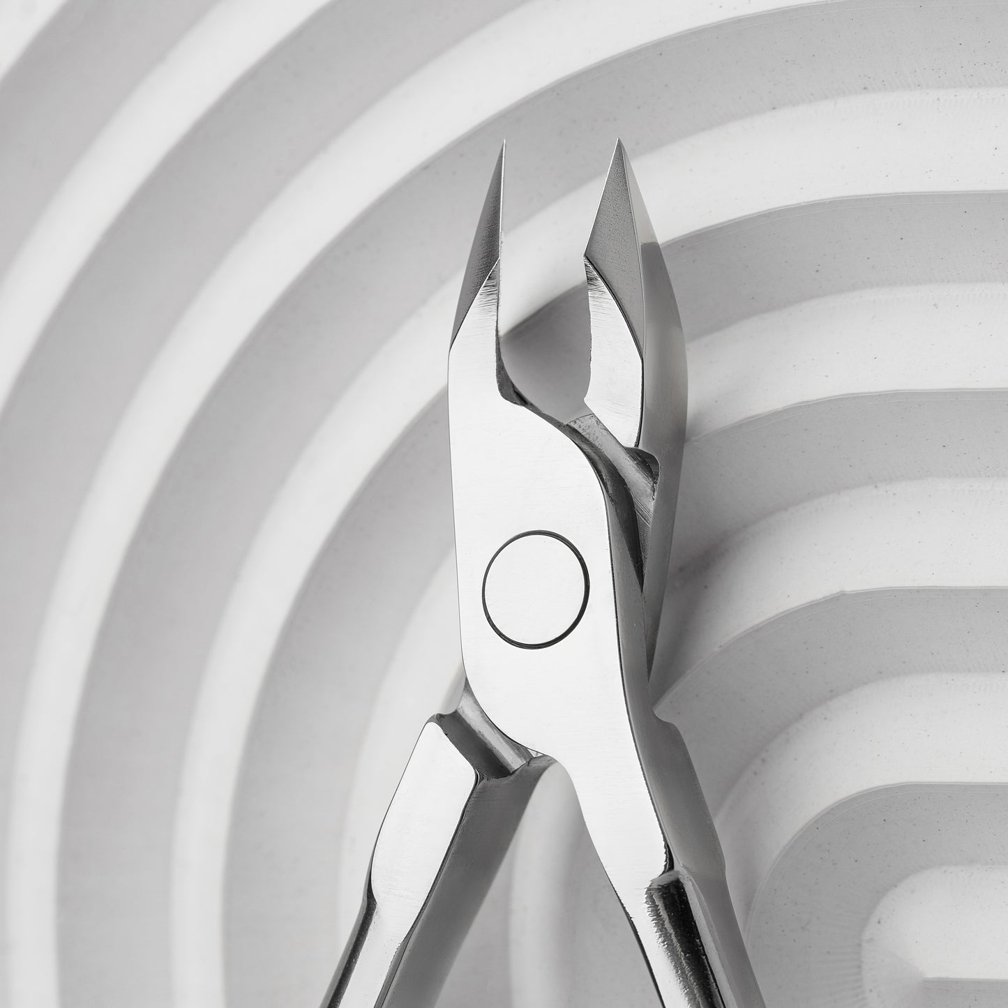 Close-up of a pair of Staleks Professional cuticle nippers 7 mm jaw EXPERT 91 against a white background with curved lines. The focus is on the sharp, precise tips of the clippers.