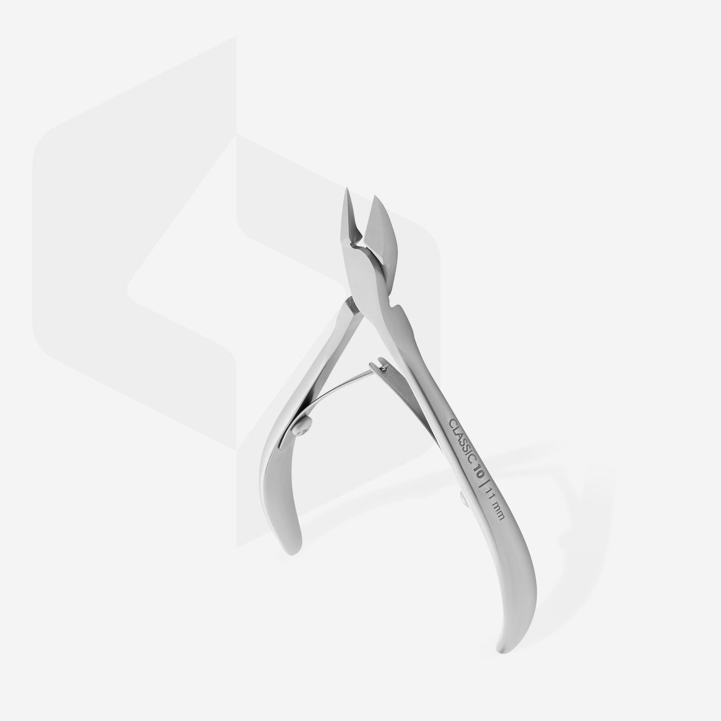 The Staleks STALEKS PRO Cuticle Nippers long 11 mm jaw CLASSIC 10, crafted from stainless steel with a curved handle and sharp blades, offers precise nail care against a backdrop of a light setting with subtle geometric design that highlights its sleek aesthetic.