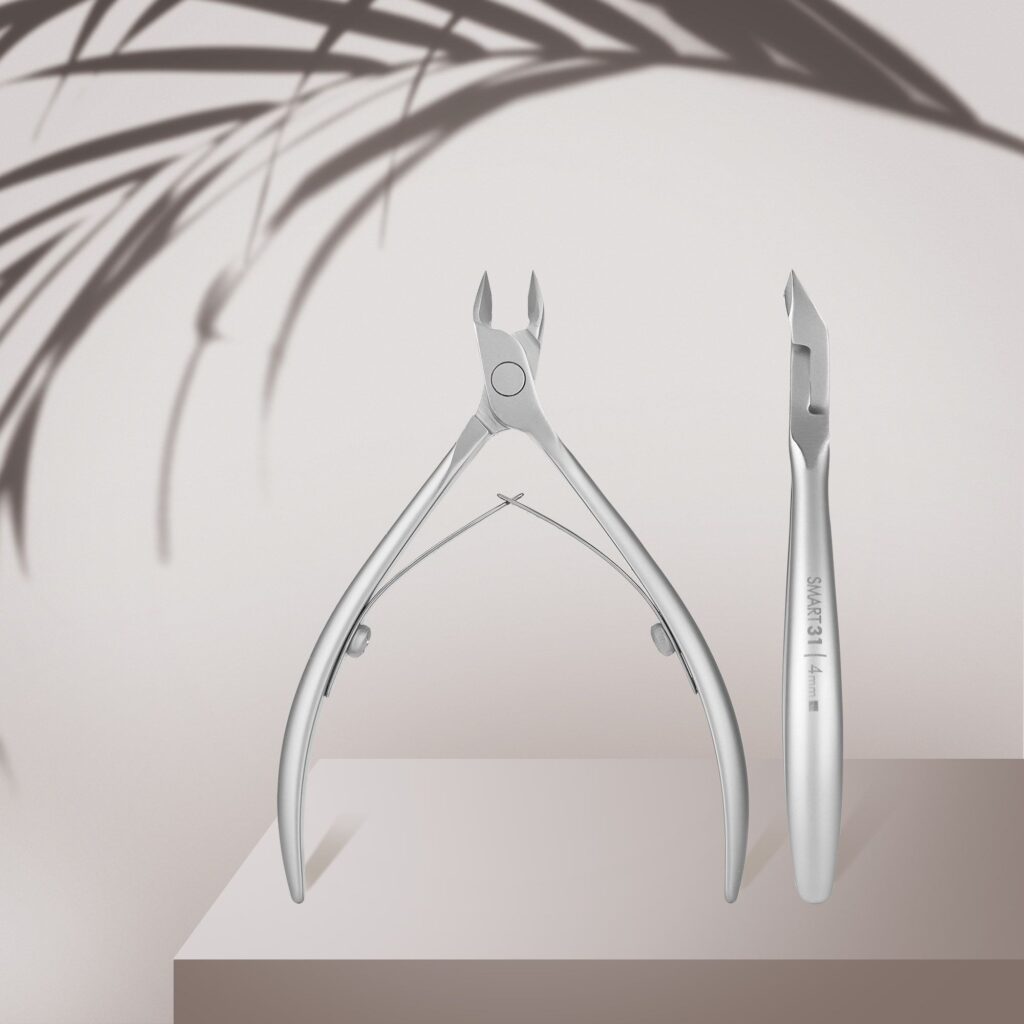 Two STALEKS PRO Professional Cuticle Nippers SMART 31 4 mm by Staleks are showcased on a beige podium, accented by blurred leaf shadows in the background for a clean, minimalist look.