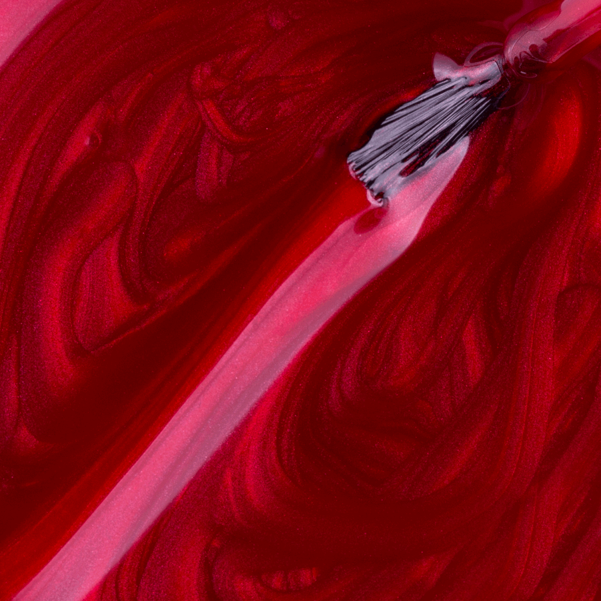 A close-up of a brush applying Impala Regular Nail Polish Pearlescent Red Amante Perolado 7.5 ml, creating smooth, swirling patterns in the rich, vibrant color.