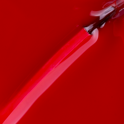 A close-up image shows a brush applying Impala Regular Nail Polish Creamy Ruby Red Madonna 7.5 ml, creating smooth, glossy streaks on a red surface.