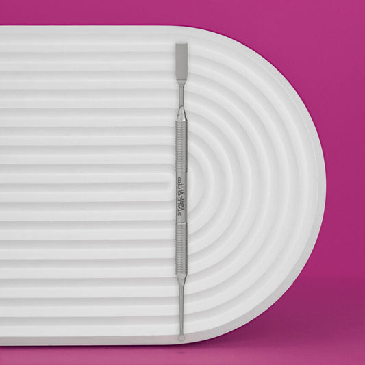 The STALEKS PRO Manicure Pusher EXPERT 51 TYPE 1 by Staleks, featuring straight flat and loop ends, sits on a white ribbed oval tray against a vibrant pink background.