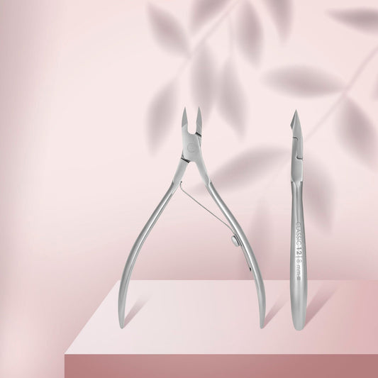 Two STALEKS PRO Cuticle Nippers CLASSIC 12 8 mm by Staleks rest on a pink surface with a soft pink background and leaf shadows; one nipper is open, the other in profile displaying engraved text—perfect for manicures and pedicures.