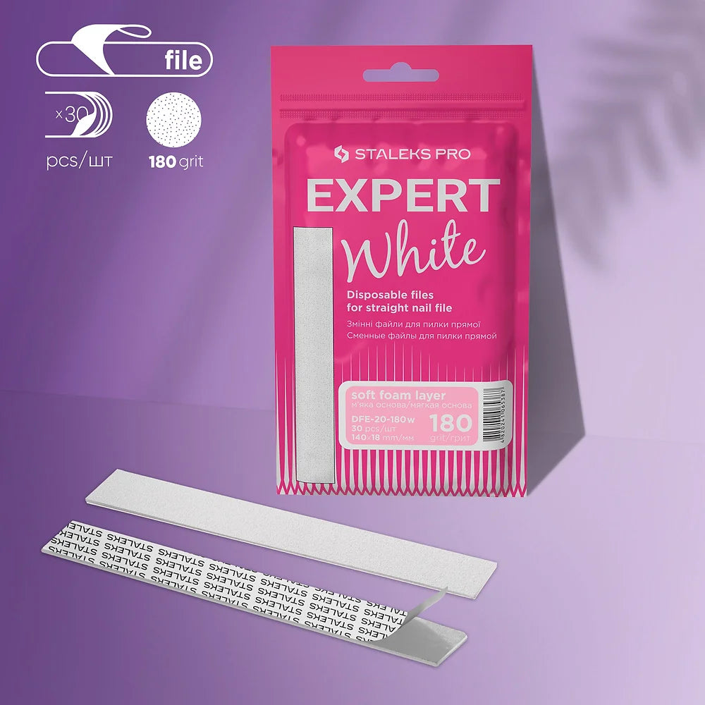 A pink pack of Staleks PRO Disposable White Files For Straight Nail File on a Soft Foam Layer EXPERT 20 (30 pcs) is displayed with three silver nail files, featuring "180 grit," soft foam, and adhesive backing against a purple background.