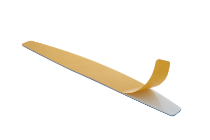 A piece of Staleks adhesive tape partially peeled off from a white surface with the sticky side visible, set against a dual-colored beige and blue background containing abrasive grit.