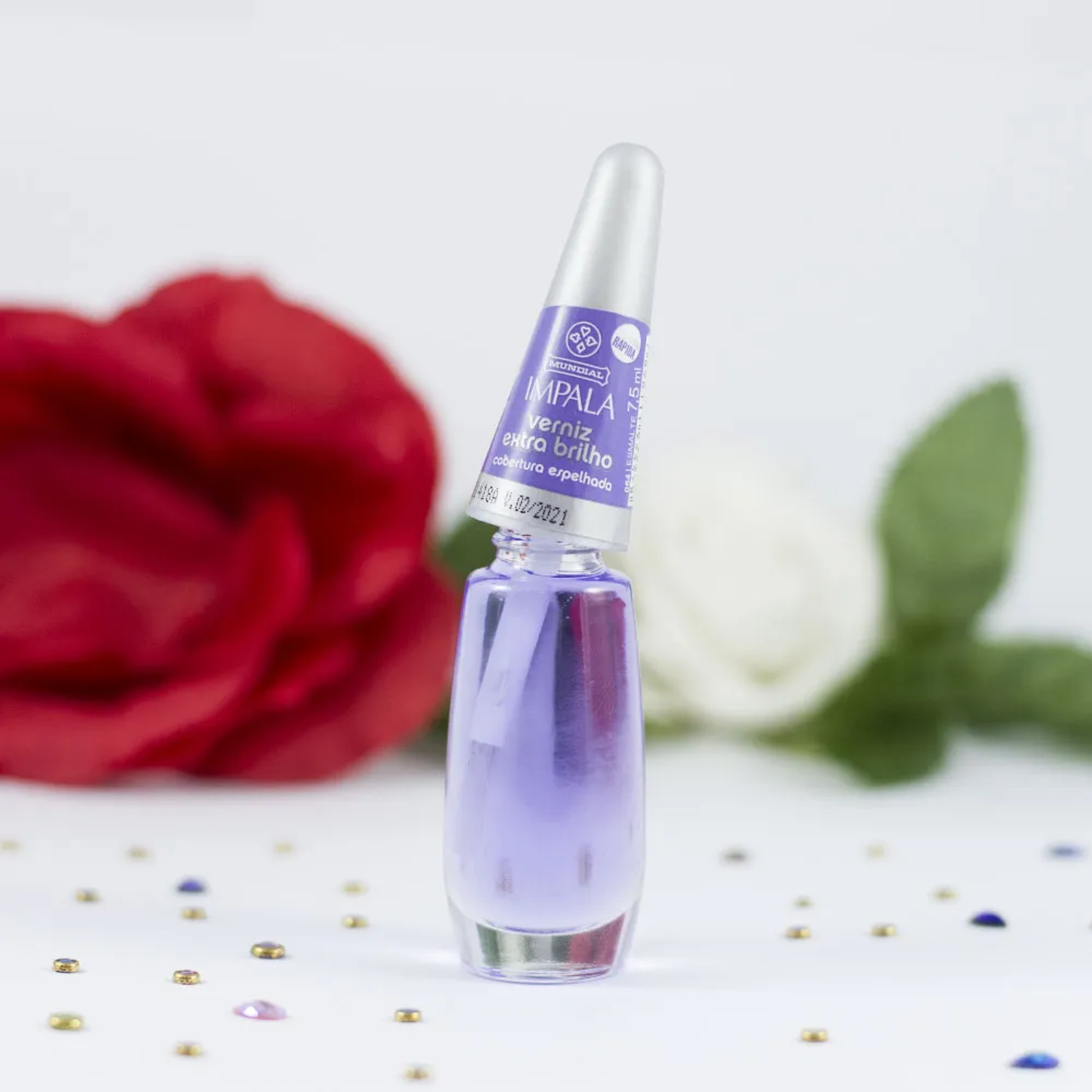 Purple nail polish bottle with red rose and white flower in the background