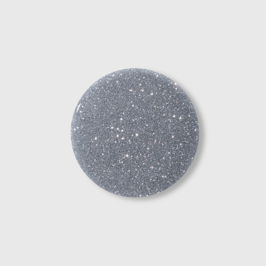 A round, silver glittery object on a plain light gray background, reminiscent of the dazzling luminous effect produced by Lumore’s LUMORE PARIS Reflective Gel Polish in the shade Margarita (9 ml), capturing the brilliance of modern nail art designs.