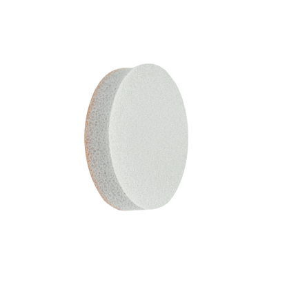 A white, round STALEKS PRO Disposable File-Sponge for Pedicure Disc PODODISC L EXPERT 25 by Staleks is shown against a black background, its spongy texture and abrasive surface highlighted by lighting from the right.
