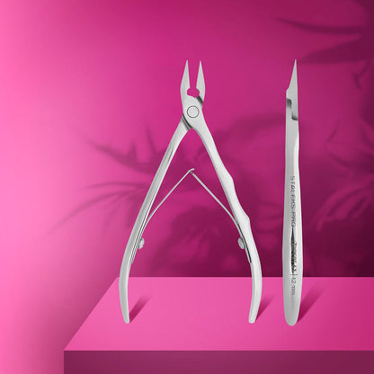 The STALEKS PRO Professional Nippers for Ingrown Toenails EXPERT 61 (12 mm) by Staleks and a cuticle pusher/remover are displayed upright on a pink platform with leaf shadows—perfect for tackling ingrown nails or a medical pedicure.