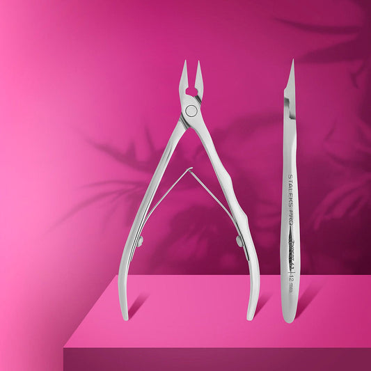 The STALEKS PRO Professional Nippers for Ingrown Toenails EXPERT 61 (12 mm) by Staleks and a cuticle pusher/remover are displayed upright on a pink platform with leaf shadows—perfect for tackling ingrown nails or a medical pedicure.