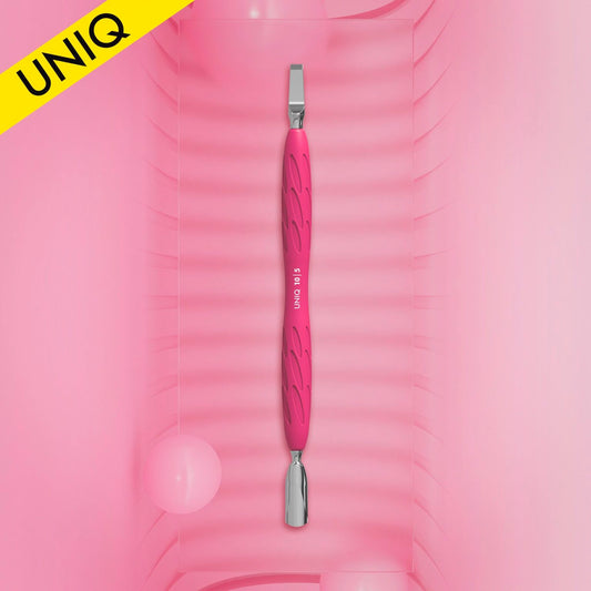 The STALEKS PRO Gummy Manicure Pusher with Silicone Handle UNIQ 10 TYPE 5, featuring a narrow rounded pusher and wide blade, is showcased vertically against a pink, textured background. A yellow corner banner displays the brand "Staleks" with "UNIQ." Pink spheres are scattered around, enhancing the chic atmosphere.