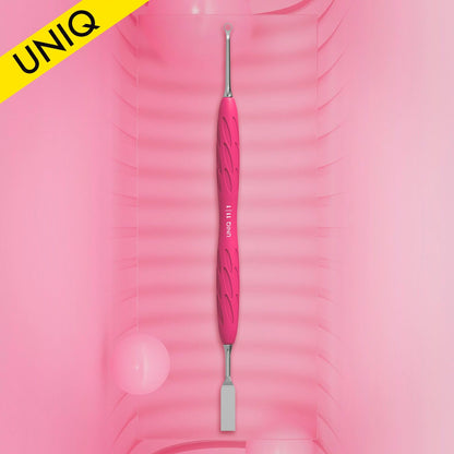A pink and silver STALEKS PRO Gummy Manicure Pusher with Silicone Handle UNIQ 11 TYPE 1 is centered against a gradient pink background. This beauty tool, designed by Staleks, showcases a textured grip with a flat straight pusher on one end and a ring on the opposite end, making it perfect for professional manicure pedicures. A yellow "UNIQ" label adorns the top left corner.
