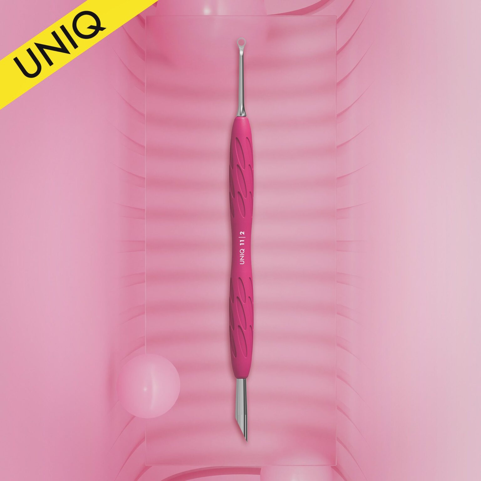 Centered on a pink background with subtle diagonal lines is the STALEKS PRO Gummy Manicure Pusher with Silicone Handle UNIQ 11 TYPE 2 from Staleks, showcasing expert craftsmanship. This dual-ended tool, perfect for manicures and pedicures, features a slanted pusher on one end and a ring on the other. A yellow banner displaying "UNIQ" decorates the top left corner.