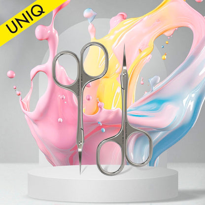 Two pairs of STALEKS PRO Asymmetric Professional Cuticle Scissors UNIQ 20 TYPE 4 with an ergonomic design are showcased on a circular stand against a vibrant pastel splash background. A yellow "Staleks" label appears at the top left, adding to the scene set against a soft gray backdrop.