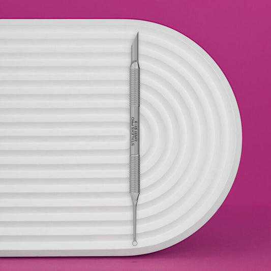 The Staleks PRO Manicure Pusher EXPERT 51 TYPE 2 (Beveled And Loop Pusher) by Staleks is shown on a white, ridged oval tray against a bright pink background.