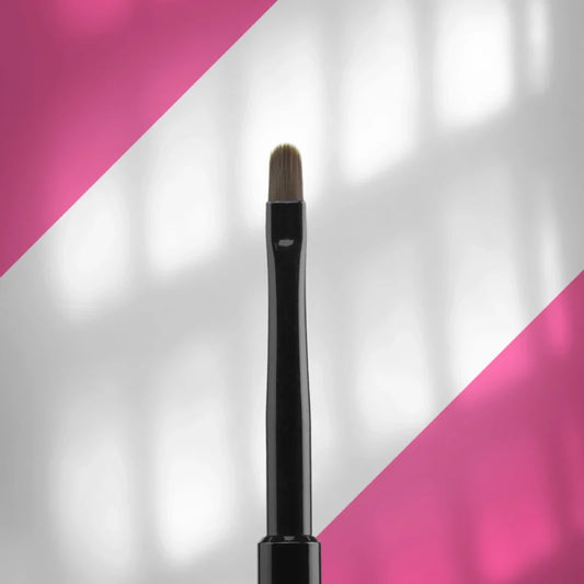 A close-up of the Staleks STALEKS PRO Brush For Gel EXPERT (4 mm width, 7 mm length) with synthetic bristles and a black handle, shown vertically against a geometric pink and white background.