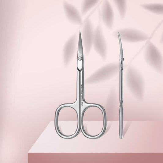 Two STALEKS PRO Cuticle Scissors CLASSIC 21 TYPE 1 from Staleks are displayed on a pink surface with leafy shadows—one scissor faces forward and the other sideways. Perfect for manicures and pedicures.