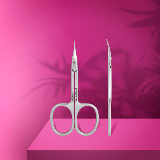 The STALEKS PRO Professional Cuticle Scissors EXPERT 50 TYPE 1 by Staleks, featuring pointed, curved stainless steel blades, stand upright on a bright pink surface with shadowy leaf patterns—ideal for any manicure routine.