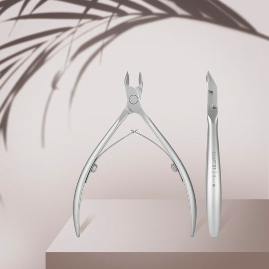 Two STALEKS PRO Professional Cuticle Nippers SMART 31 4 mm by Staleks are showcased on a beige podium, accented by blurred leaf shadows in the background for a clean, minimalist look.