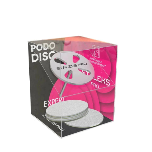 Transparent cube packaging showcases the STALEKS PRO Pedicure Disc PODODISC and Set of Disposable File 5 pcs by Staleks. Stainless steel flat discs and disposable files are visible, with a pink background and product branding text.