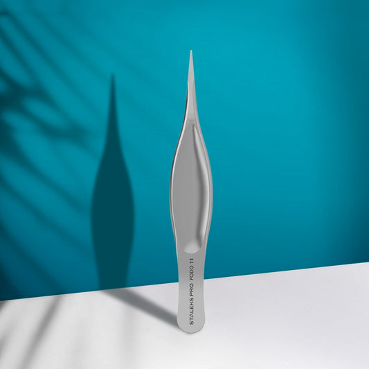 The STALEKS PRO Podology Splinter Tweezers Small PODO 11 by Staleks stands upright on a white surface under a teal background, ideal for ingrown nail care and recognized for its corrosion resistance.